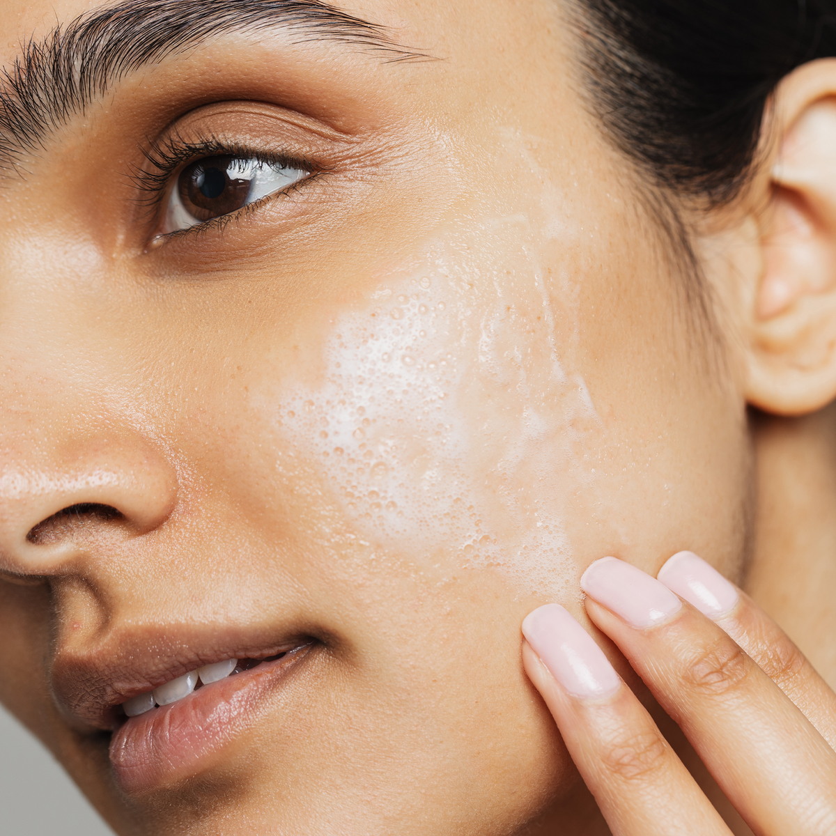 Close up of a person applying active clarity gel cleanser to the side of their face. 