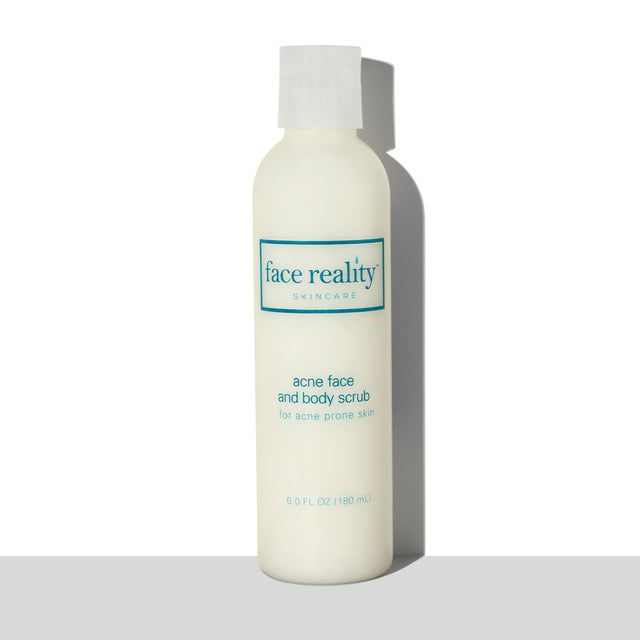 Clear six ounce bottle of Face Reality acne face and body scrub in front of a white background on a grey surface  - view 1