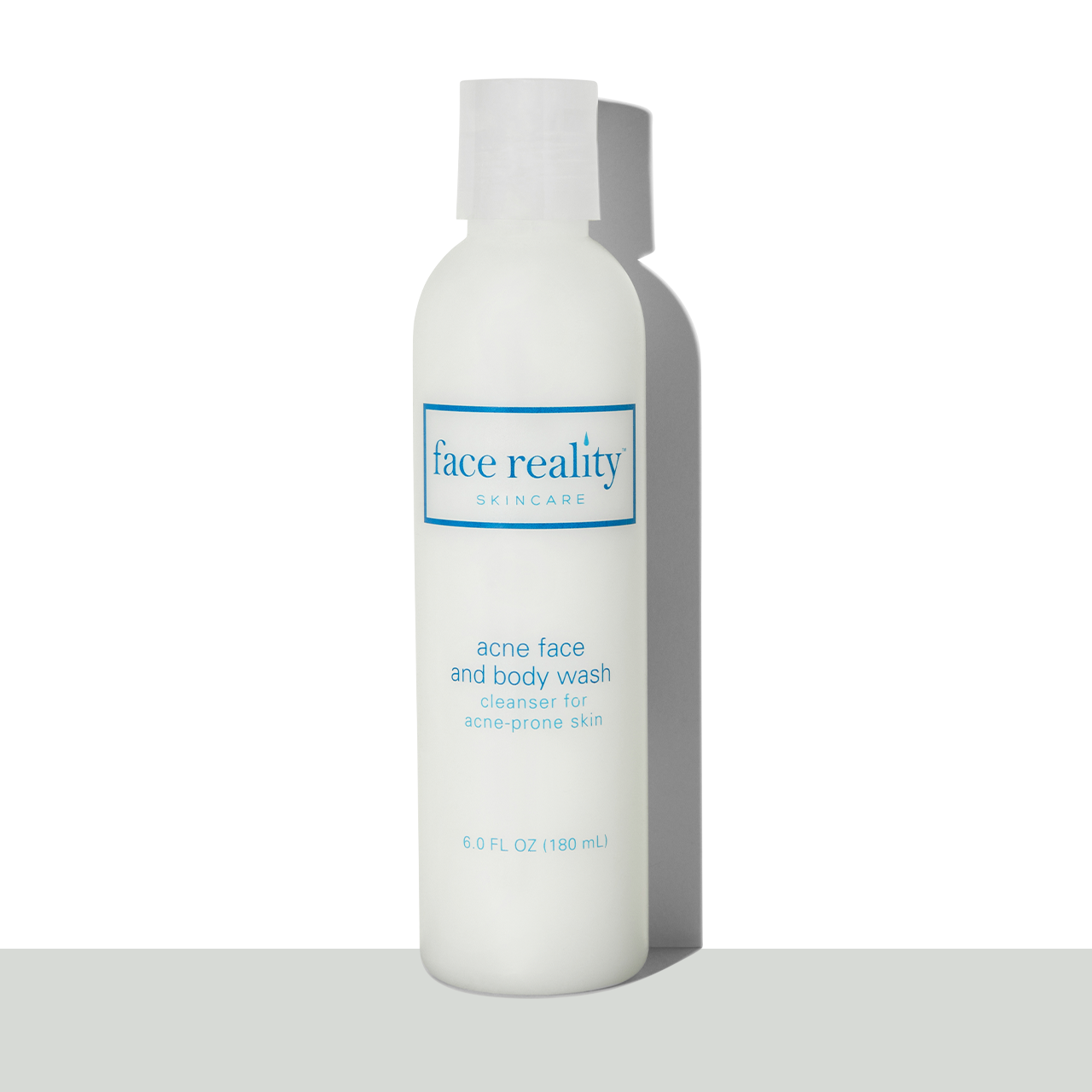 Clear six ounce bottle of Face Reality acne face and body wash in front of a white background on a grey surface