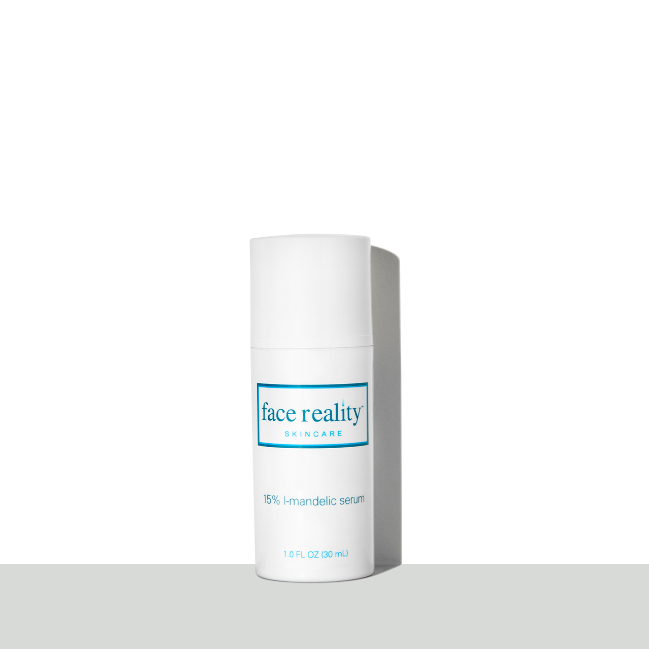 a white one fluid ounce bottle of Face Reality fifteen percent L-mandelic Serum in front of a white background on a grey surface