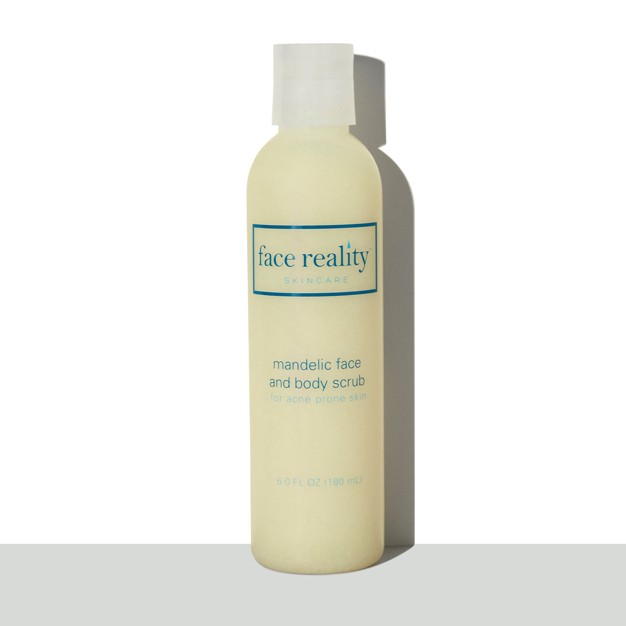Clear six ounce bottle of Face Reality mandelic face and body scrub in front of a white background on a grey surface