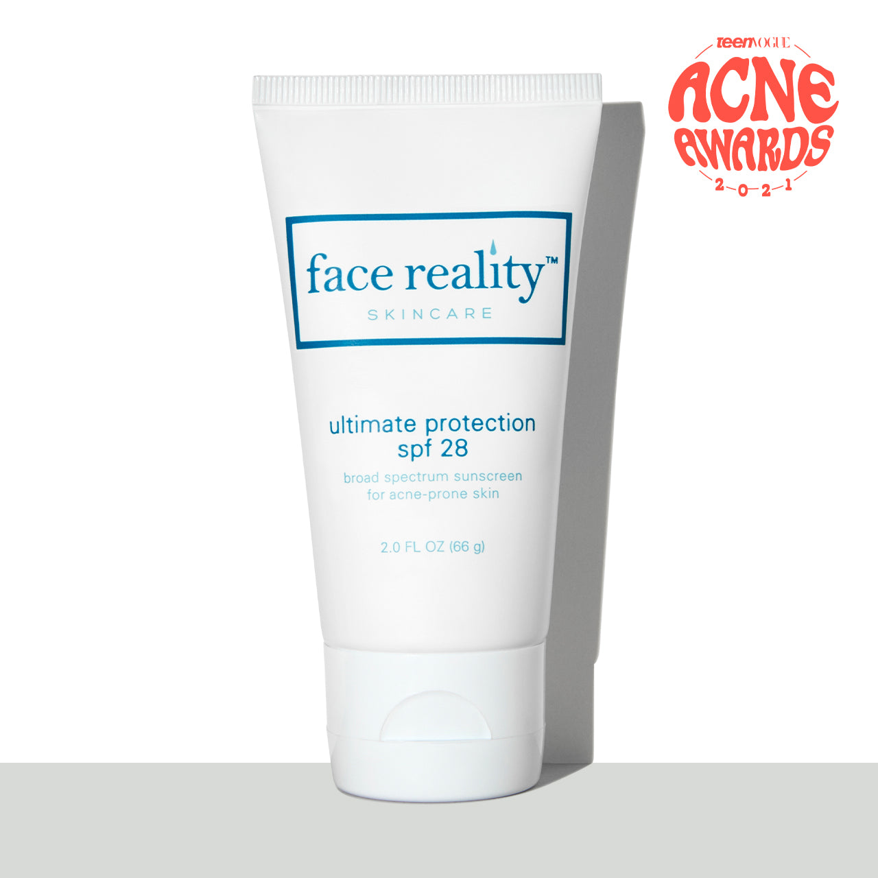white two ounce bottle of Face Reality ultimate protection spf 28 sunscreen in front of white background on a grey surface with teen vogue acne awards 2021 award stamp